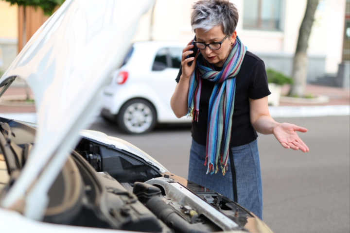 a-woman-stands-in-front-of-a-car-with-an-open-hood-and-call-to-service-department-or-calls-a-tow-truck