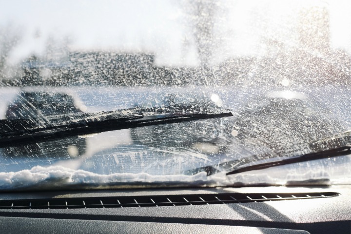 Car windshield with road grime on glass surface.  