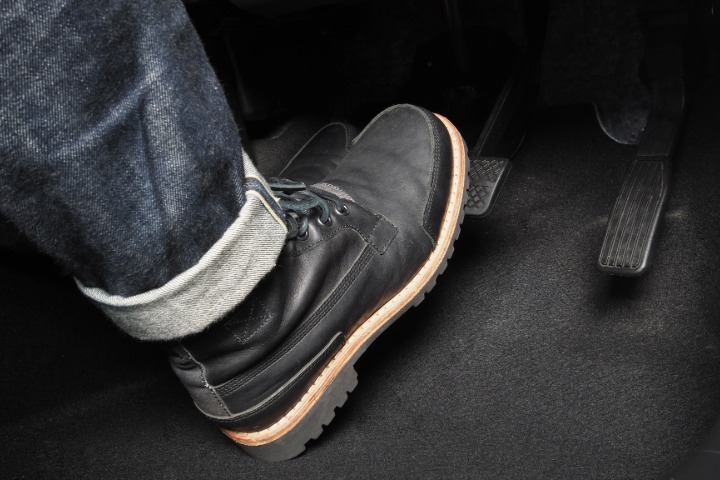 Close up the foot pressing foot pedal of a car to drive ahead.