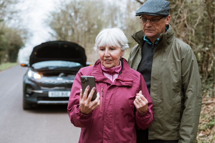 Elderly couple on roadside, car breakdown.